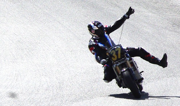 Thad Wolff of Moto Electra celebrates fifth finish on parade lap sticking out arm and leg on corkscrew