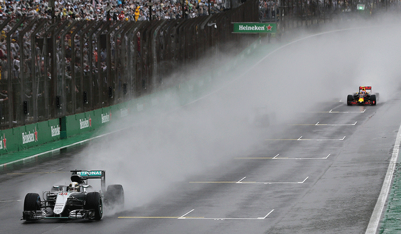 Mercedes' Lewis Hamilton of Britain (L) competes under heavy rainfall.