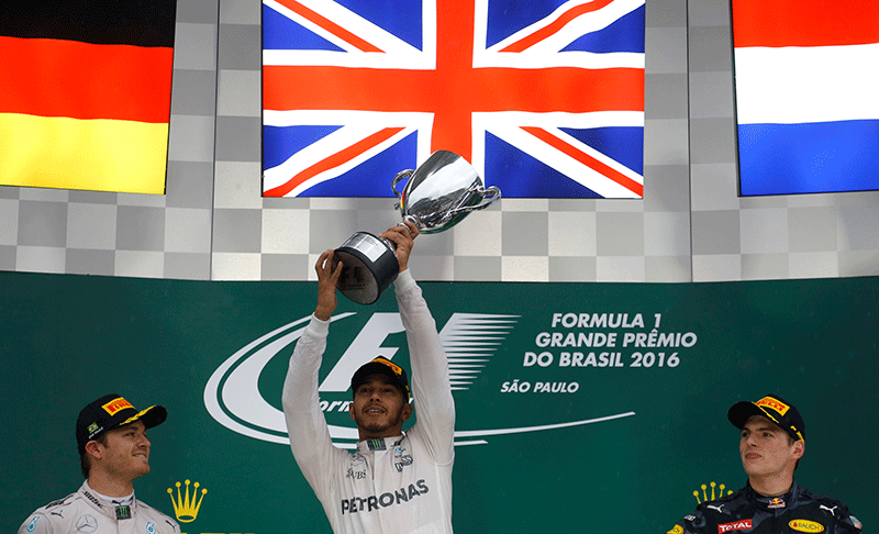 Mercedes' Lewis Hamilton of Britain raises his trophy during the victory ceremony after winning the race as second placed finisher and teammate Nico Rosberg of Germany (L) and third placed finisher Red Bull's Max Verstappen of the Netherlands look on
