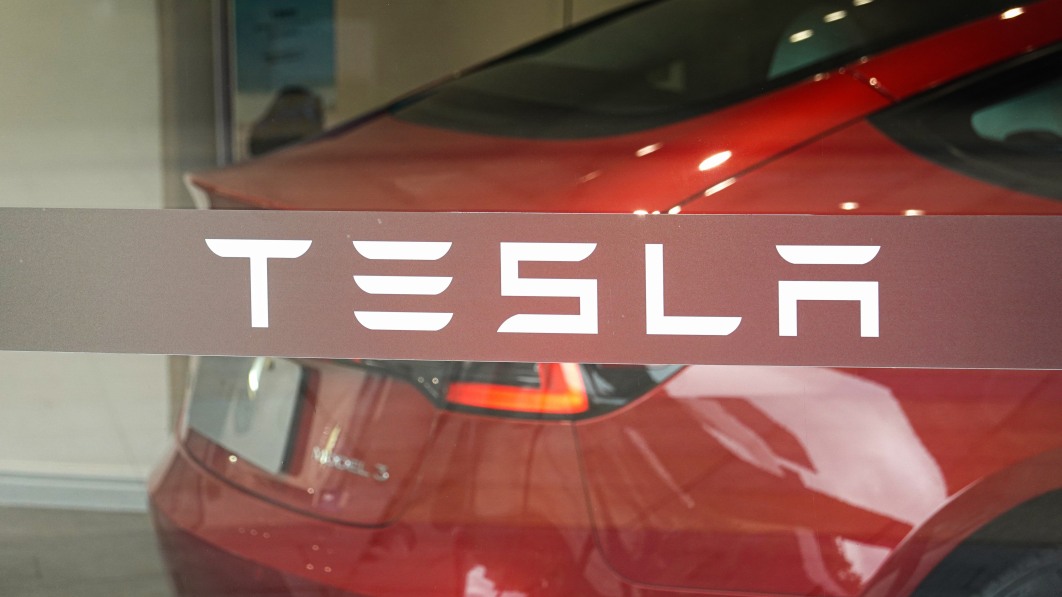 the tesla logo is seen on the store s glass window