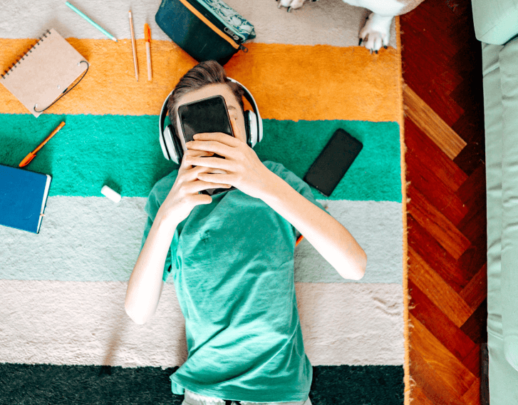 boy wearing headphones laying down looking at phone