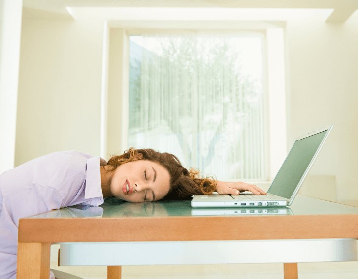 Girl asleep at desk with hand on a laptop